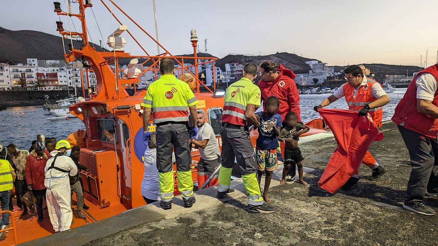 Flyktninger hjelpes i land av redningspersonell.